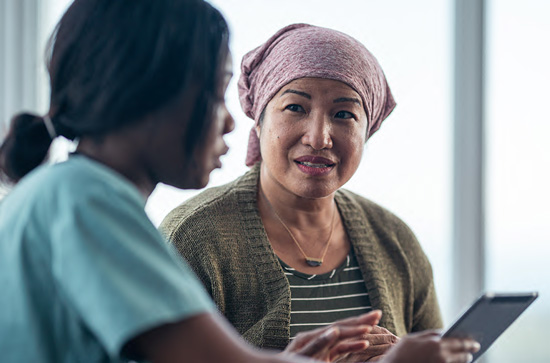 Woman with a pink head scarf speaking with a nurse