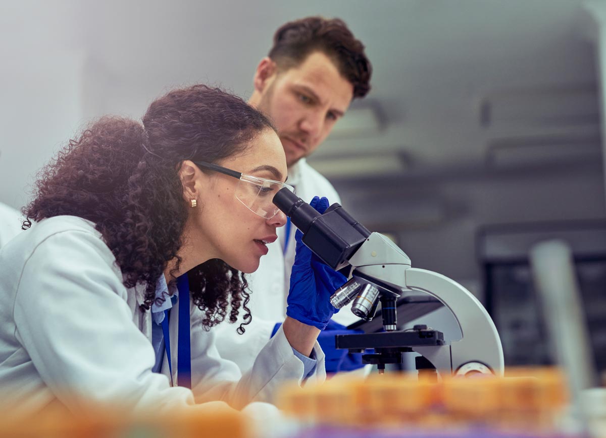 Researchers in lab coats looking into a microscope